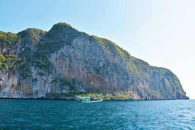 白色船附近的海绿色和灰色山白天
